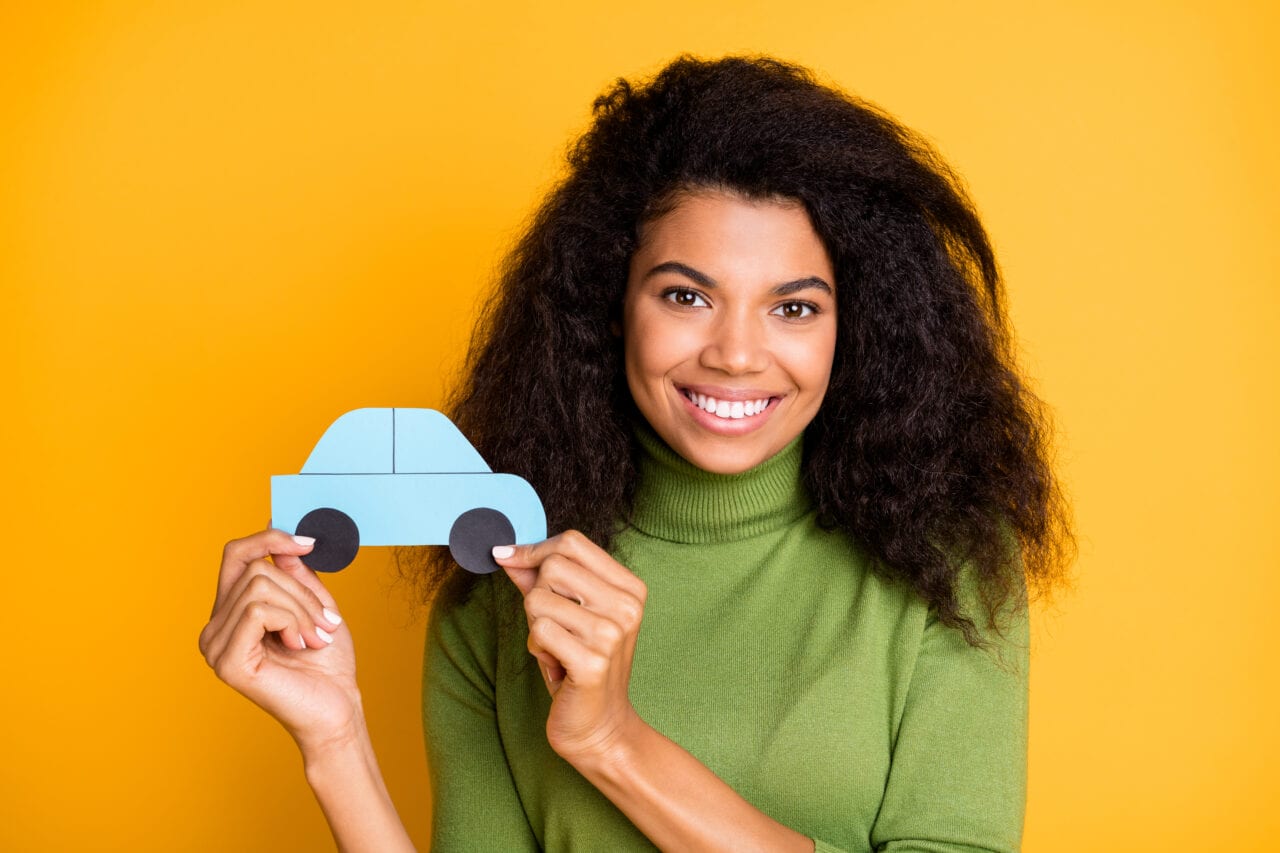 Jeune femme portant une petite voiture imprimée sur fond orange